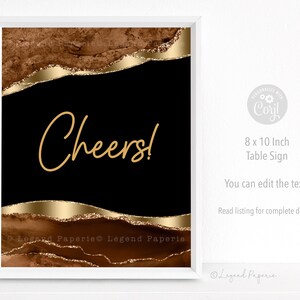 May include: A printable 8x10 inch table sign with a black background and gold glitter accents. The text "Cheers!" is written in gold lettering. The sign is ideal for a party or celebration.