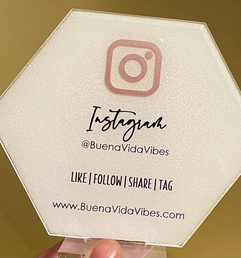 May include: A white hexagonal sign with a pink Instagram logo and the text "Instagram @BuenaVidaVibes LIKE | FOLLOW | SHARE | TAG www.BuenaVidaVibes.com"