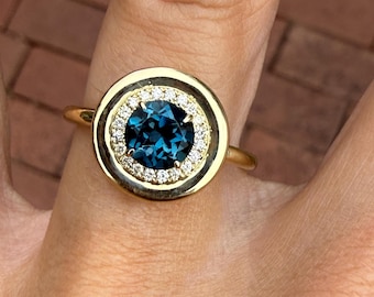 Anillo de cóctel redondo con topacio azul de Londres y halo de diamantes naturales en oro amarillo de 10k.