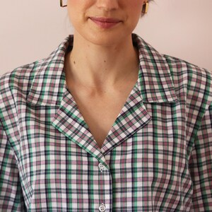 May include: A green, white, pink, and black plaid button-up shirt with a collar.