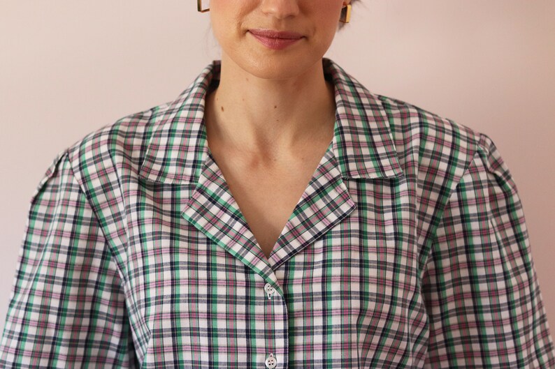 May include: A green, white, pink, and black plaid button-up shirt with a collar.