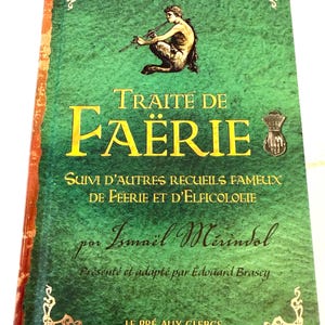 May include: A hardcover book titled "Traite de Faërie" with a green cover and gold lettering. The cover features an illustration of a mythological figure playing a flute. The book's spine is red.