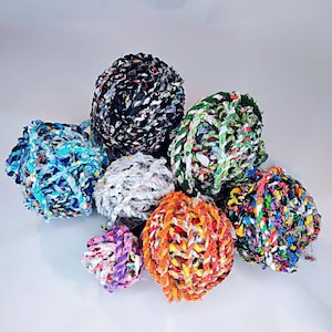May include: A collection of colorful yarn balls made from recycled fabric scraps. The balls are various sizes and shapes, with a mix of patterns and textures.
