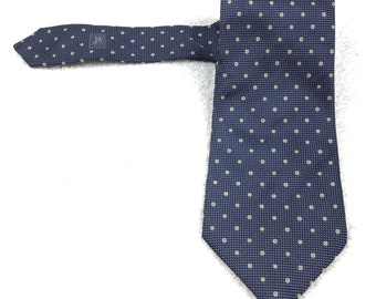 May include: A navy blue silk tie with a white polka dot pattern. The tie has a narrow width and a pointed tip.
