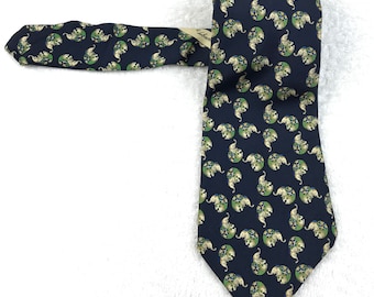 Puede incluir: Una corbata de seda azul oscuro con un patrón repetido de elefantes blancos en círculos verdes. La corbata tiene una etiqueta que dice "Liberace".