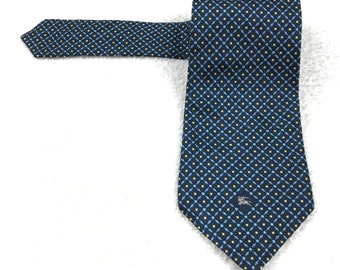 May include: A navy blue silk tie with a geometric pattern of yellow and light blue squares. The tie has a small logo in the center.