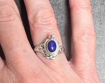 May include: A silver ring with a blue oval-shaped stone set in a decorative filigree design.