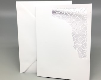 Puede incluir: Una tarjeta blanca con un diseño decorativo, intrincado, cortado con láser en el lado derecho. El diseño es un patrón repetitivo de círculos y óvalos.