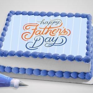 May include: A rectangular cake with blue frosting and the words "happy Father's Day" in orange and blue script. The cake has a light blue striped background and is decorated with blue frosting around the edges. A pastry bag with blue frosting is in the foreground.