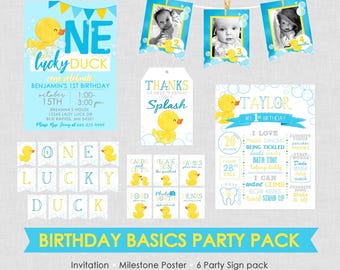 May include: A party pack with a "One Lucky Duck" theme, featuring invitations, banners, and photo displays. The design includes a blue and yellow color scheme with images of a cartoon duck. The pack is for a first birthday.