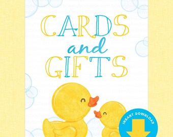 May include: A white sign with the text CARDS and GIFTS in blue and yellow lettering. Below the text are two yellow rubber ducks. The background features light blue bubbles. A blue circular badge with a yellow arrow and text INSTANT DOWNLOAD.