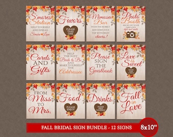 May include: A set of twelve fall-themed bridal signs with text like "S'mores Station", "Favors", and "Mimosa Bar". Each sign is 8x10 inches and features a wooden background with autumn leaf accents. The signs are designed for a wedding.