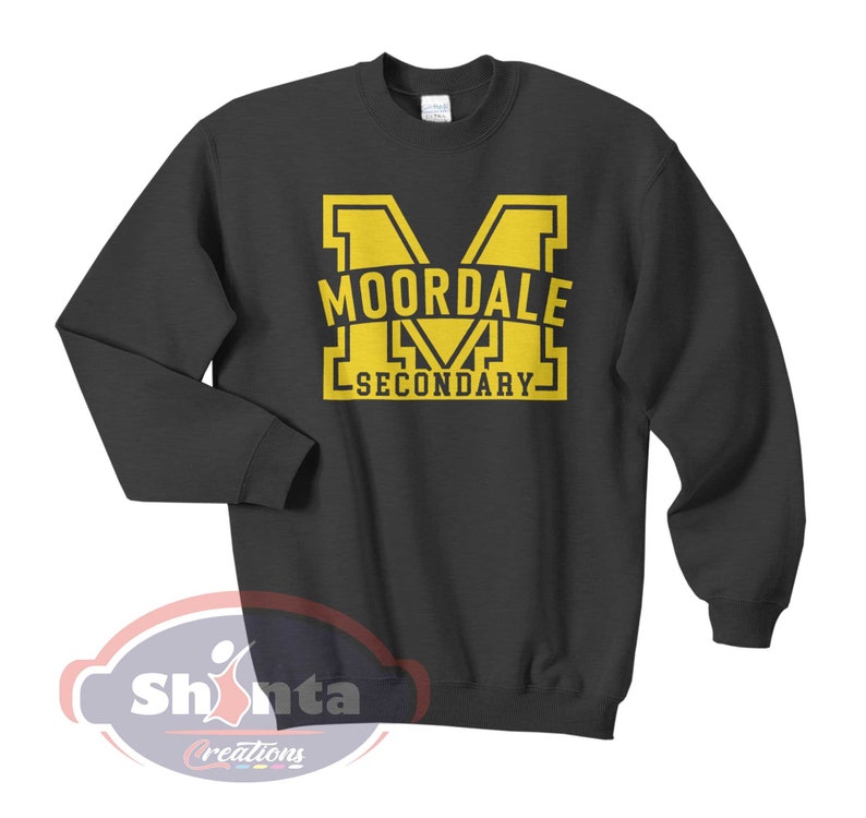 K&ouml;nnte beinhalten: Ein dunkelgrauer Pullover mit einem gelben Aufdruck des Buchstabens "M" und dem Text "MOORDALE SECONDARY".