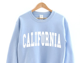 Peut inclure: Un sweat-shirt bleu clair avec le mot "CALIFORNIA" imprimé en blanc sur le devant.
