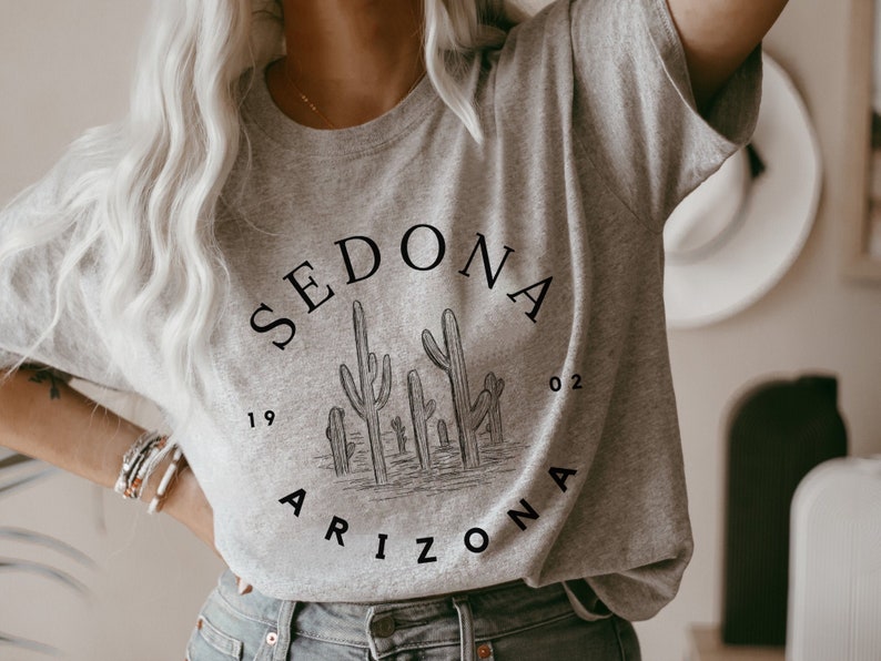 May include: A gray t-shirt with a black graphic design featuring the text "SEDONA ARIZONA 19 02" and a silhouette of cacti.