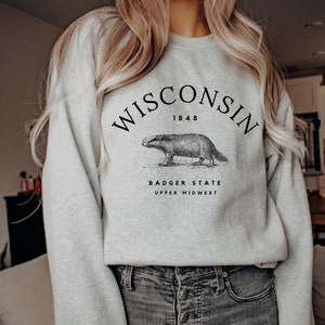 May include: Gray sweatshirt with a black graphic print of a badger and the text "WISCONSIN 1848 BADGER STATE UPPER MIDWEST".