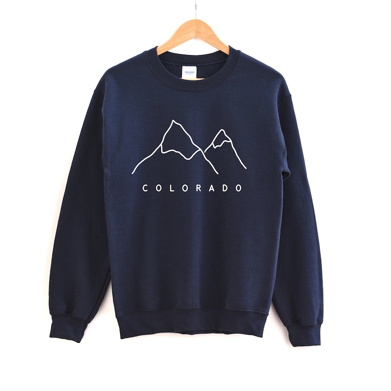 May include: A navy blue sweatshirt with a white outline of two mountains and the word "COLORADO" printed on the front.