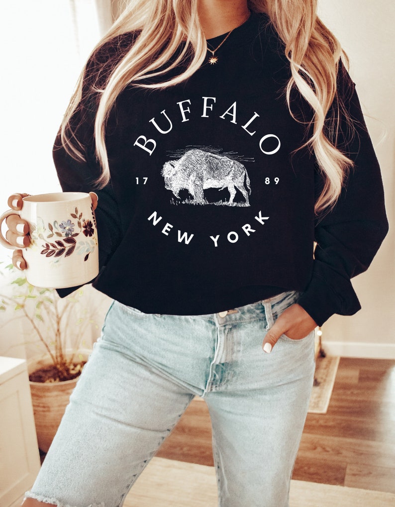 May include: Black sweatshirt with a white graphic print of a buffalo and the text "BUFFALO 1789 NEW YORK".