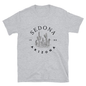 May include: A gray t-shirt with a black graphic of a circle with the text "SEDONA ARIZONA" and a drawing of cacti inside the circle. The text "19 02" is on either side of the cacti.