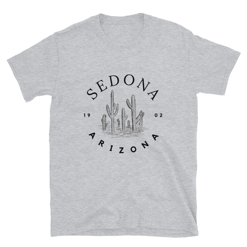 May include: A gray t-shirt with a black graphic of a circle with the text "SEDONA ARIZONA" and a drawing of cacti inside the circle. The text "19 02" is on either side of the cacti.