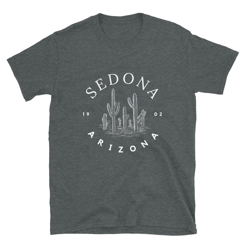 May include: A dark heather grey t-shirt with a white circle graphic featuring the text "SEDONA ARIZONA 1902" and a drawing of cacti.