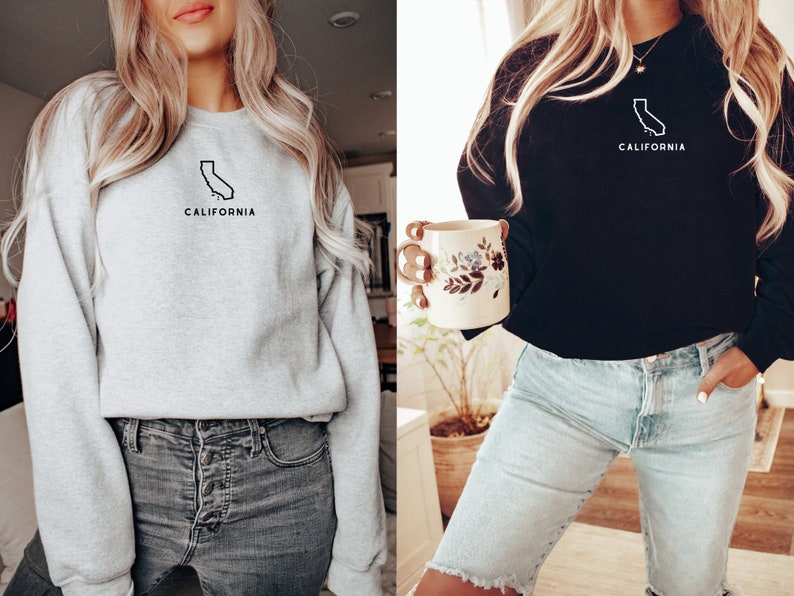 May include: Two women wearing sweatshirts with a California outline and the word "California" printed on them. One sweatshirt is grey and the other is black.