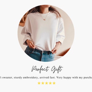 May include: A white sweatshirt with a simple design. The sweatshirt is being worn by a person with their hands in their pockets. The text "Perfect Gift" is written below the image. The text "Soft sweater, sturdy embroidery, arrived fast. Very happy with my purchase." is written below the text "Perfect Gift". Five gold stars are below the text.