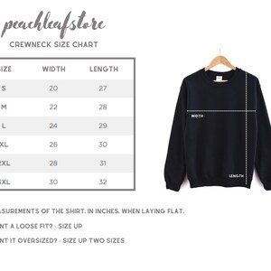 May include: A black crewneck sweatshirt hanging on a wooden hanger, with a size chart to the left. The chart lists sizes S to 3XL, with width and length measurements in inches. The text reads "peachleafstore CREWNECK SIZE CHART."
