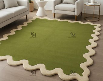 May include: A large, olive green rug with a wavy, cream-colored border. The rug is placed on a hardwood floor and is surrounded by furniture, including a sofa and armchair. The rug's design adds a unique touch to the room's decor.