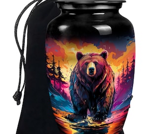 May include: Black ceramic urn featuring a colourful image of a bear standing in a stream against a sunset backdrop. The urn is supplied with a black velvet drawstring bag.