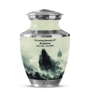 May include: A decorative urn with a silver lid and base, depicting a spectral figure in a misty landscape. The urn is inscribed with "In Loving Memory of Andrew Oct/1956-Jan/2026". The urn has a light green and silver colour scheme.