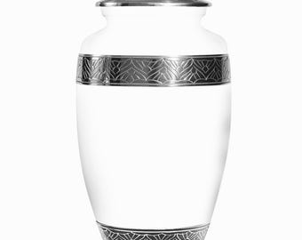May include: A white cremation urn with a silver-colored lid and decorative bands. The bands feature a repeating leaf pattern. The urn is a classic, elegant design for memorializing a loved one.