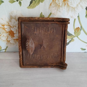May include: A rusty cast iron door with a handle and the words "Sveta" and "A.M.A.N.O.T.I.S." embossed on the front.