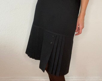 May include: A black midi skirt with a pleated hem and a button detail. The skirt is fitted at the waist and falls to the knee.