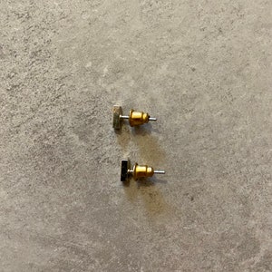 Puede incluir: Un par de pendientes de botón rectangulares de plata con postes dorados.