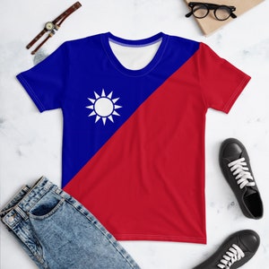 Puede incluir: Una camiseta azul y roja con un sol blanco y 12 puntos sobre un fondo azul. La camiseta está dividida en diagonal, con el lado azul a la izquierda y el lado rojo a la derecha.