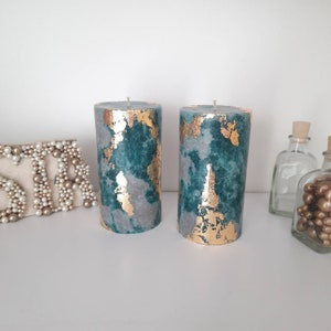 Puede incluir: Dos velas cil&iacute;ndricas con un dise&ntilde;o veteado en verde azulado y gris, acentuadas con pan de oro. Las velas no tienen aroma y tienen una est&eacute;tica sencilla y elegante. Son adecuadas para la decoraci&oacute;n del hogar o como regalo.