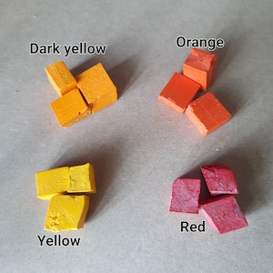 以下が含まれることがあります： 正方形に配置された4つの小さな色のチョークブロック。色は濃い黄色、オレンジ、黄色、赤です。