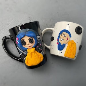 May include: Two ceramic mugs with a black and white design featuring a cartoon character with blue hair and a yellow jacket. The character is from the film "Coraline".