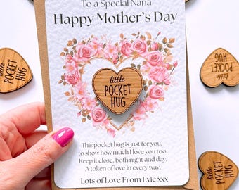Puede incluir: Una tarjeta con un diseño floral y el texto "To a Special Nana Happy Mother's Day". Un corazón de madera con el texto "little pocket hug" está unido a la tarjeta.
