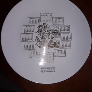 May include: A white ceramic plate with a gold border and a calendar for the year 1969. The calendar features each month with the days of the week and dates. The plate also includes the text "Sheaffer's Oil Service, Chevron Heating Oils, Blain, Pa. and Elliottsburg, Pa."