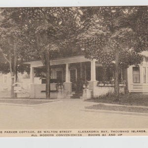 Puede incluir: Postal vintage en blanco y negro del Parker Cottage, un edificio con un porche sostenido por columnas blancas. La postal incluye la dirección, la ubicación y el texto "All Modern Conveniences". Los árboles enmarcan el edificio.