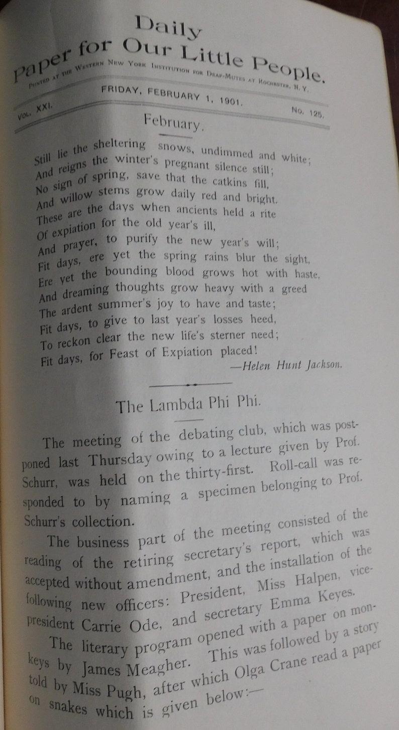 May include: A black and white newspaper clipping from the Daily Paper for Our Little People, dated February 1, 1901. The article discusses the meeting of the Lambda Phi Phi debating club, which was postponed due to a lecture by Professor Schurr. The meeting included the reading of the retiring secretary's report, the installation of new officers, and a literary program featuring a paper on monkeys by James Meagher and a story by Miss Pugh, followed by a paper on snakes by Olga Crane.