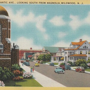 Puede incluir: Postal vintage que representa una escena callejera en Wildwood, Nueva Jersey. La imagen muestra un edificio de ladrillo con una c&uacute;pula dorada, una calle con coches y casas. El texto en la parte superior dice "VIEW ALONG ATLANTIC AVE., LOOKING SOUTH FROM MAGNOLIA, WILDWOOD, N. J."