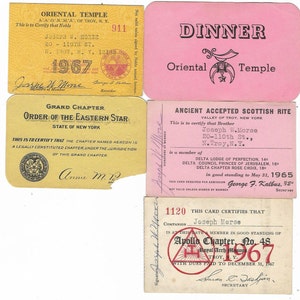 Puede incluir: Cuatro tarjetas de membresía para el Templo Oriental, la Orden de la Estrella del Este, el Rito Escocés Antiguo y Aceptado y el Capítulo Apolo. Las tarjetas son amarillas, rosadas y blancas con texto negro y presentan símbolos masónicos.