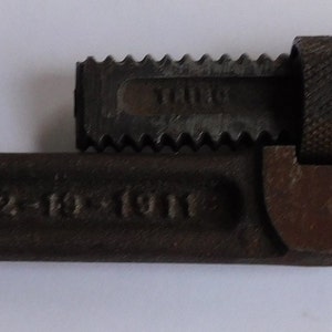 May include: A rusty, old, adjustable wrench with the brand name "TRIMO" and the text "SIZE 1 1/2"  "PAT'D 12-18-1911" on the handle.