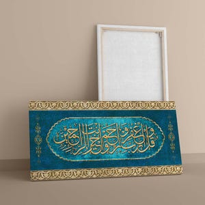 May include: A rectangular canvas art piece with gold Arabic calligraphy on a teal background. The artwork has a gold decorative border and is leaning against a white framed canvas.