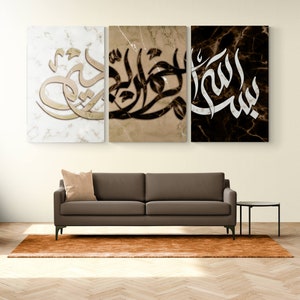 May include: Three canvas prints with a marble background featuring Arabic calligraphy in gold and black. The prints are hung on a white wall above a brown sofa.