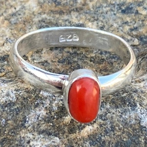 Pu&ograve; includere: Un anello d'argento con una pietra di corallo rosso. L'anello &egrave; contrassegnato dal numero "925" sulla fascia interna.