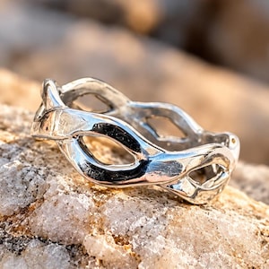 May include: A polished silver ring featuring an openwork design composed of interconnected, smooth, rounded metal loops that form a continuous, repeating pattern around the entire circumference of the band, creating a delicate and airy appearance.